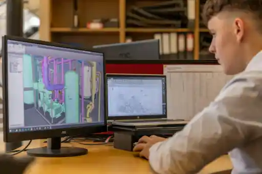 Engineer studying digital training materials on a screen in a modern workspace."